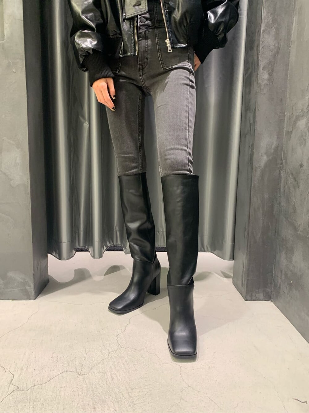 ブラック系のブーツ、グレー系のデニムパンツ、ブラック系のブルゾンを着用したレディースの秋コーディネートの5枚目の写真