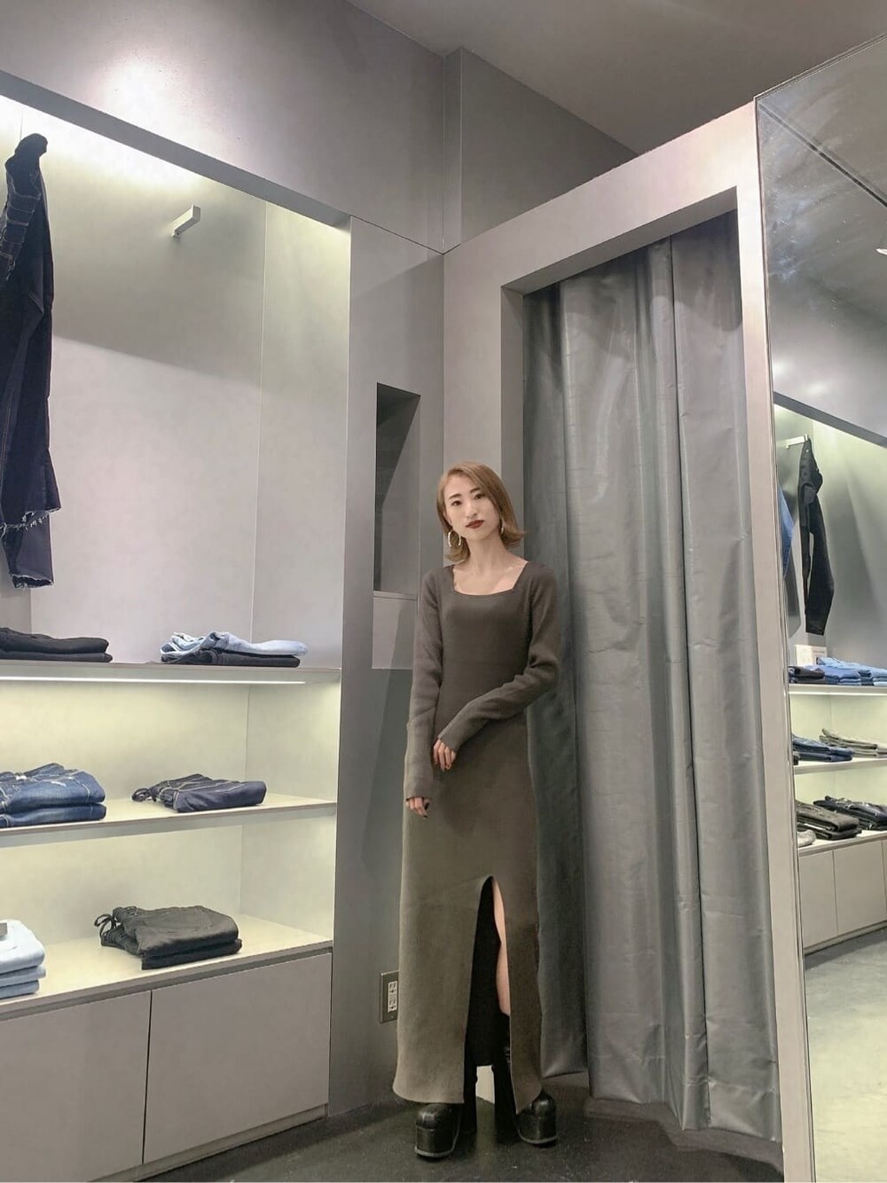 ブラック系のブーツ、グレー系のワンピース、ゴールド系のピアス（両耳用）を着用したレディースの秋コーディネートの3枚目の写真