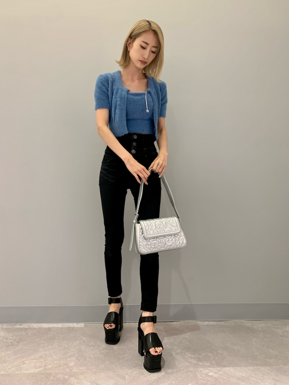 ブラック系のデニムパンツ、ブルー系のニット/セーター、シルバー系のハンドバッグを着用したレディースの夏コーディネートの2枚目の写真