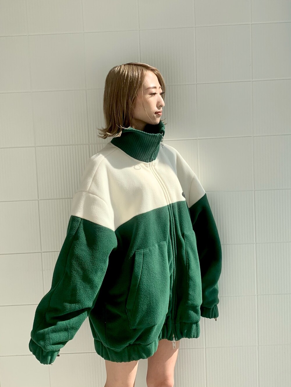 グリーン系のブルゾン、ブラック系のハンドバッグ、ブラック系のブーツを着用したレディースの秋コーディネートの5枚目の写真