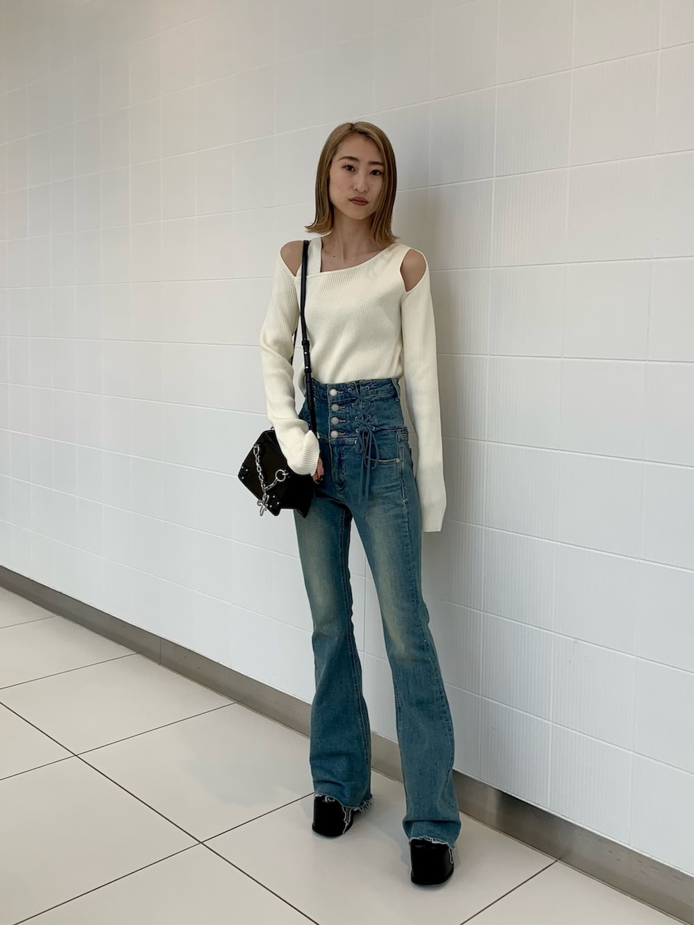 ブラック系のショルダーバッグ、ホワイト系のニット/セーター、ブラック系のブーツを着用したレディースの冬コーディネートの3枚目の写真