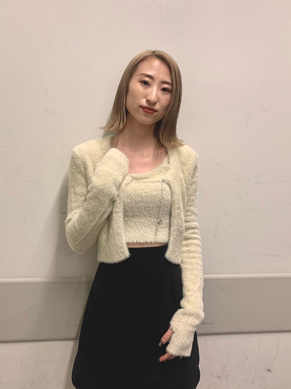 ブラック系のスカート、ホワイト系のニット/セーター、ブラック系のブーツを着用したレディースの冬コーディネートの5枚目の写真