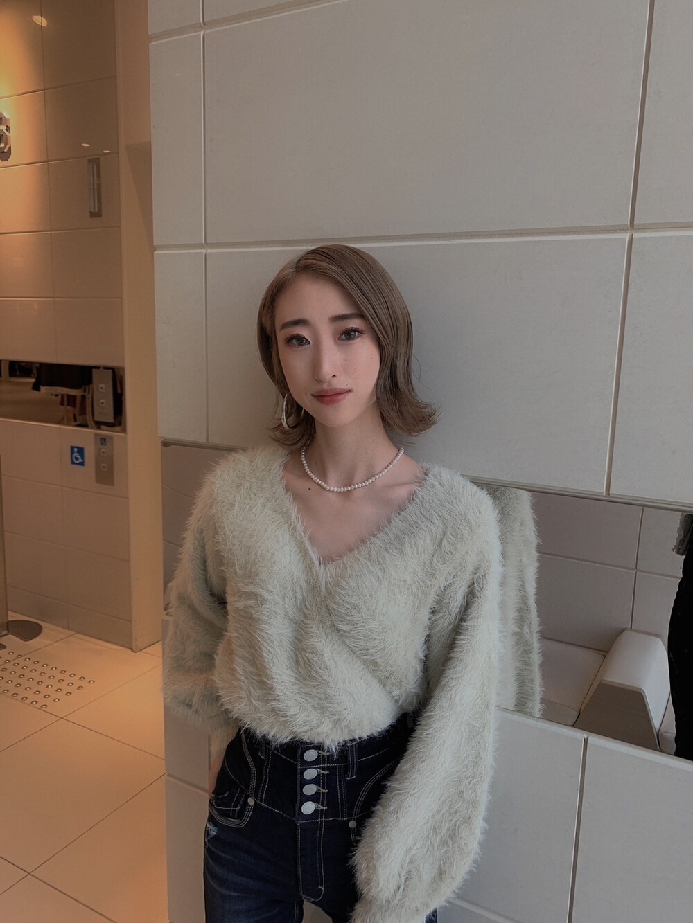 グレー系のニット/セーター、ブルー系のデニムパンツ、ブラック系のブーツを着用したレディースの冬コーディネートの5枚目の写真