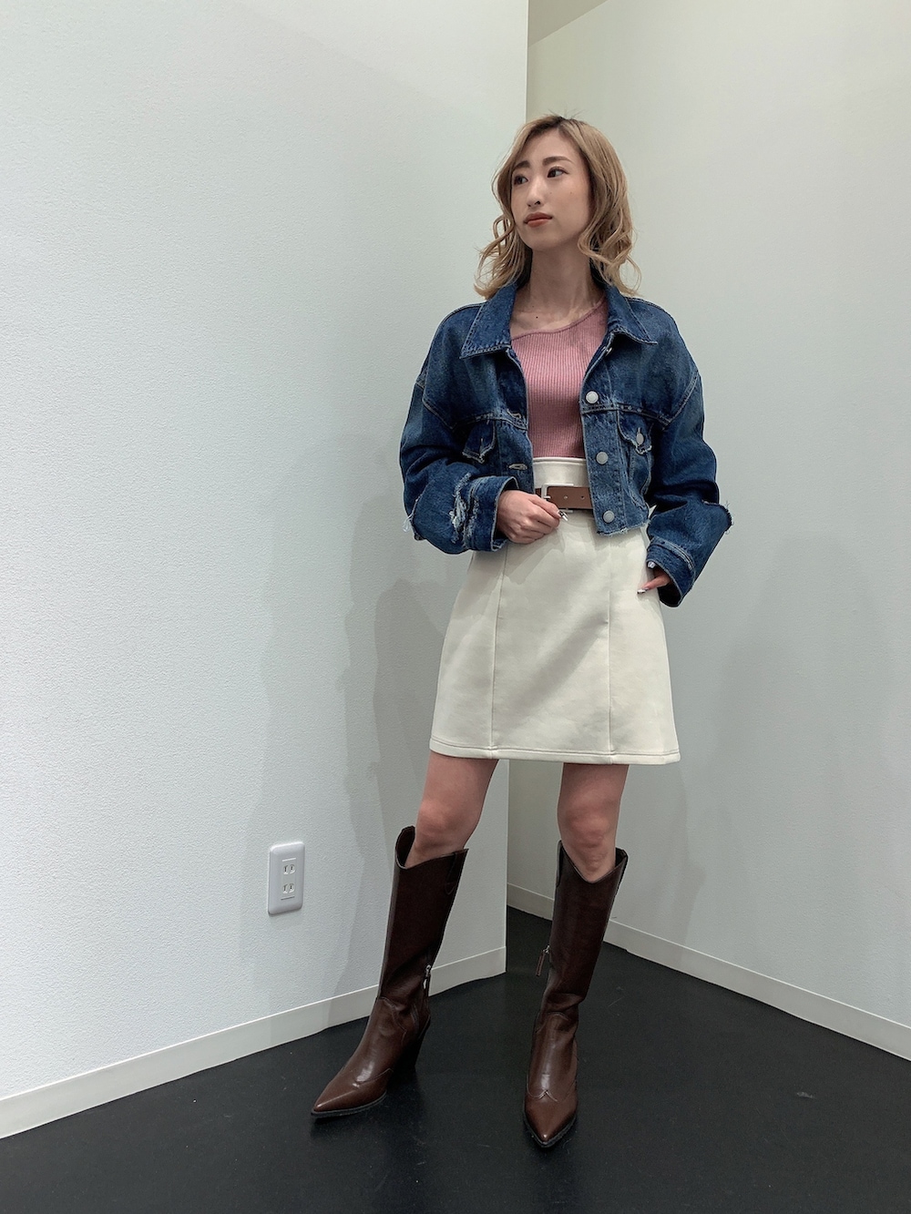 ブルー系のデニムジャケット、ピンク系のニット/セーター、ホワイト系のスカートを着用したレディースの春コーディネートの3枚目の写真