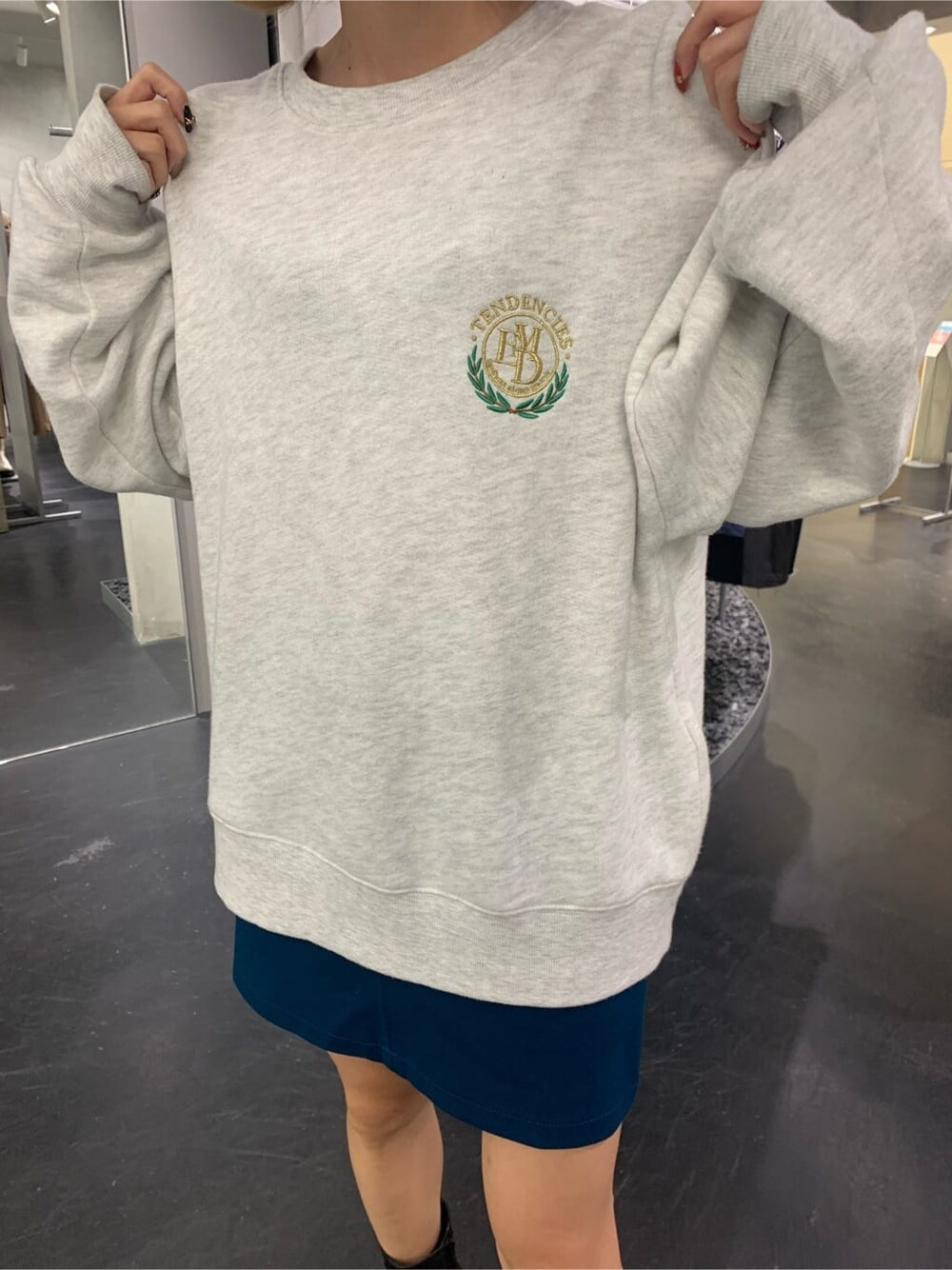 グレー系のスウェット、ブルー系のスカート、ブラック系のブーツを着用したレディースの秋コーディネートの6枚目の写真