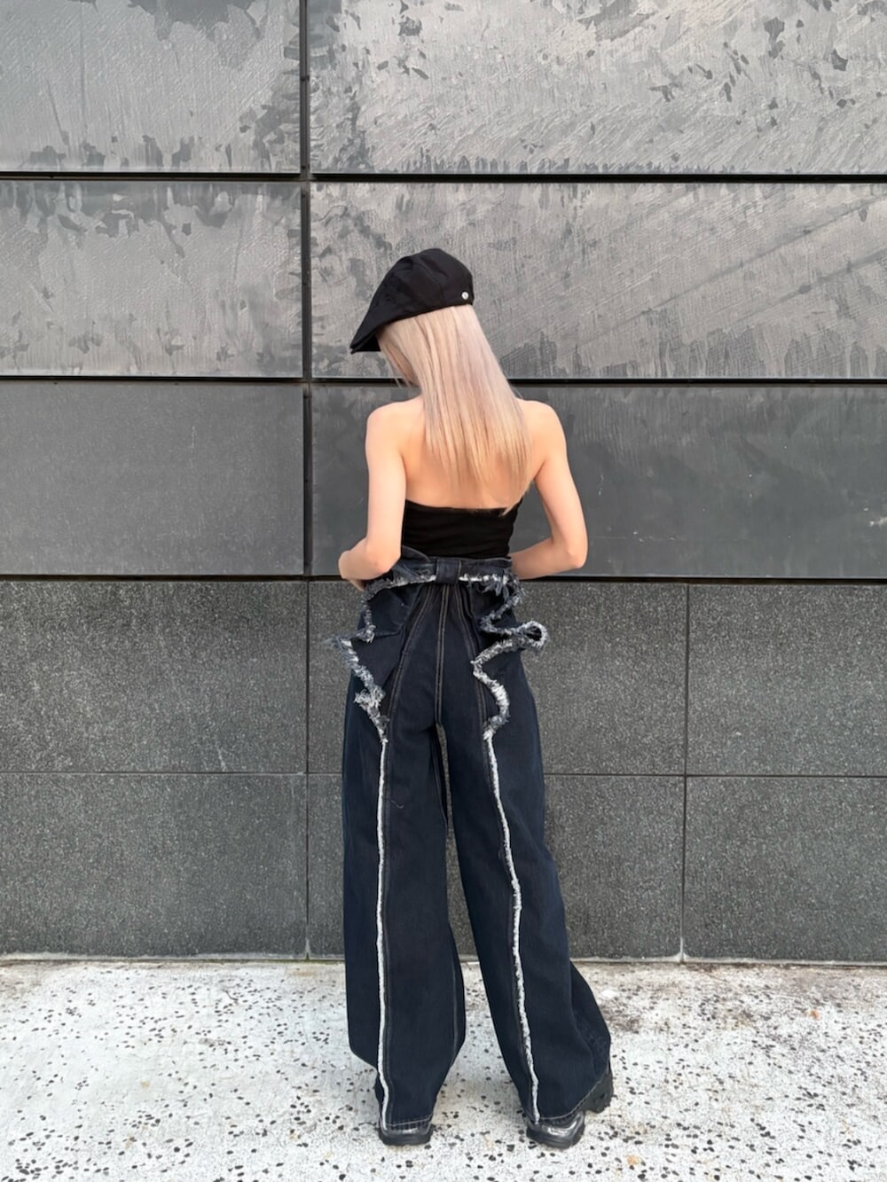 ブラック系のタンクトップ、ブルー系のデニムパンツ、ブラック系のサンダルを着用したレディースの春コーディネートの5枚目の写真