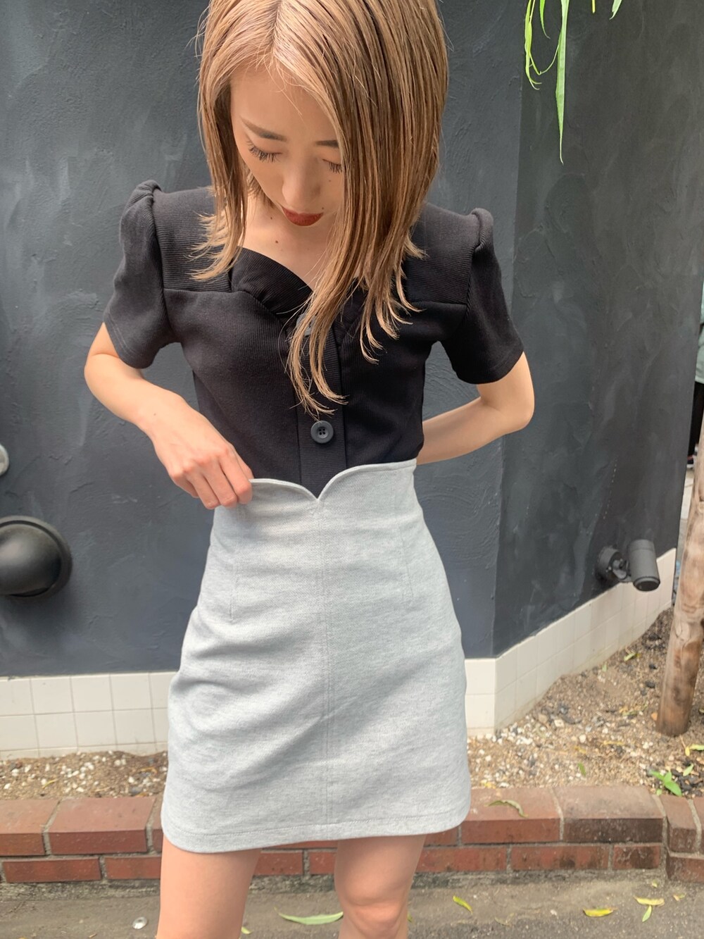 ブラック系のTシャツ/カットソー、グレー系のスカート、ブラック系のサンダルを着用したレディースの春コーディネートの6枚目の写真