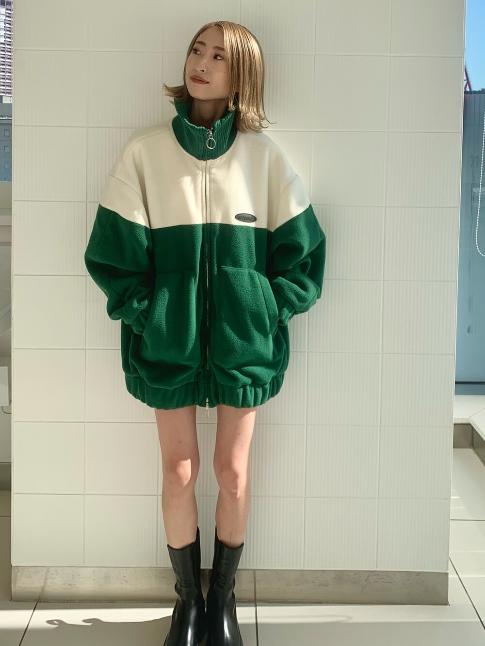 グリーン系のブルゾン、ブラック系のハンドバッグ、ブラック系のブーツを着用したレディースの秋コーディネートの3枚目の写真