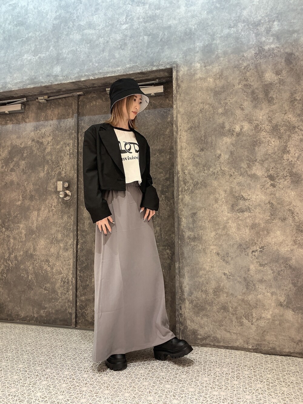 ブラック系のテーラードジャケット、ホワイト系のTシャツ/カットソー、グレー系のスカートを着用したレディースの冬コーディネートの2枚目の写真