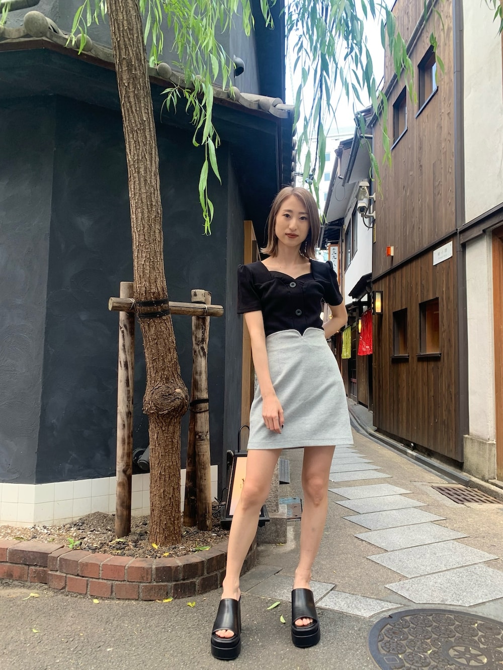 ブラック系のTシャツ/カットソー、グレー系のスカート、ブラック系のサンダルを着用したレディースの春コーディネートの3枚目の写真