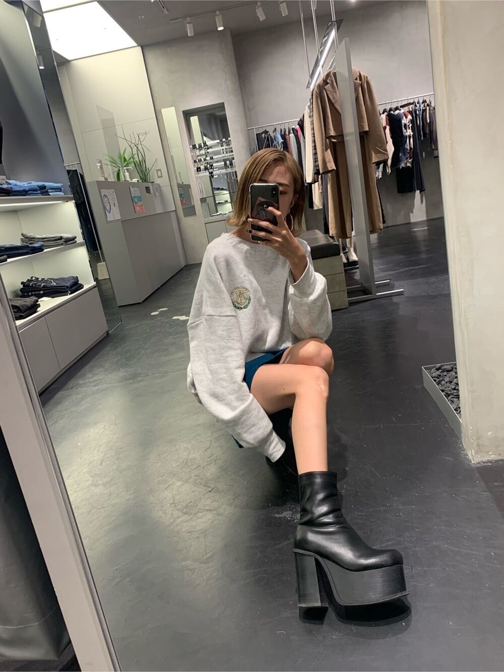 グレー系のスウェット、ブルー系のスカート、ブラック系のブーツを着用したレディースの秋コーディネートの2枚目の写真