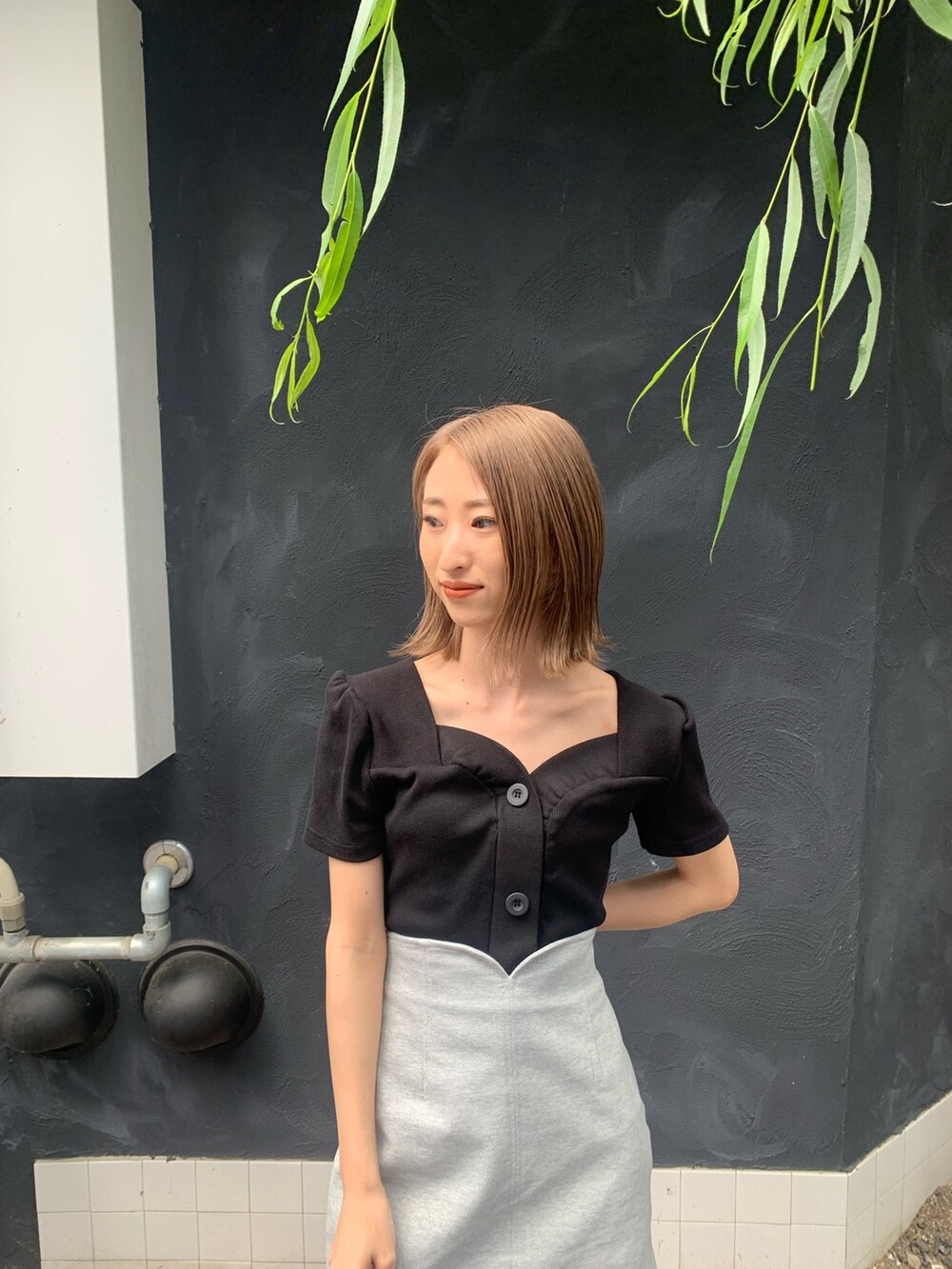 ブラック系のTシャツ/カットソー、グレー系のスカート、ブラック系のサンダルを着用したレディースの春コーディネートの4枚目の写真