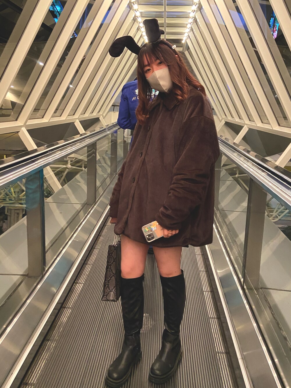 グリーン系のステンカラーコート、グレー系のショルダーバッグ、ブラック系のブーツを着用したレディースの秋コーディネートの2枚目の写真