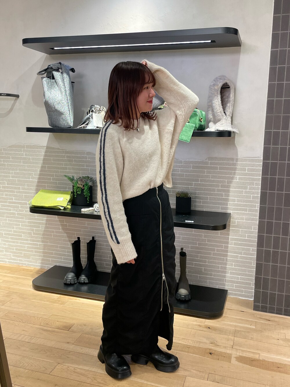 ブラック系のスカート、ホワイト系のニット/セーター、ブラック系のブーツを着用したレディースの冬コーディネートの2枚目の写真