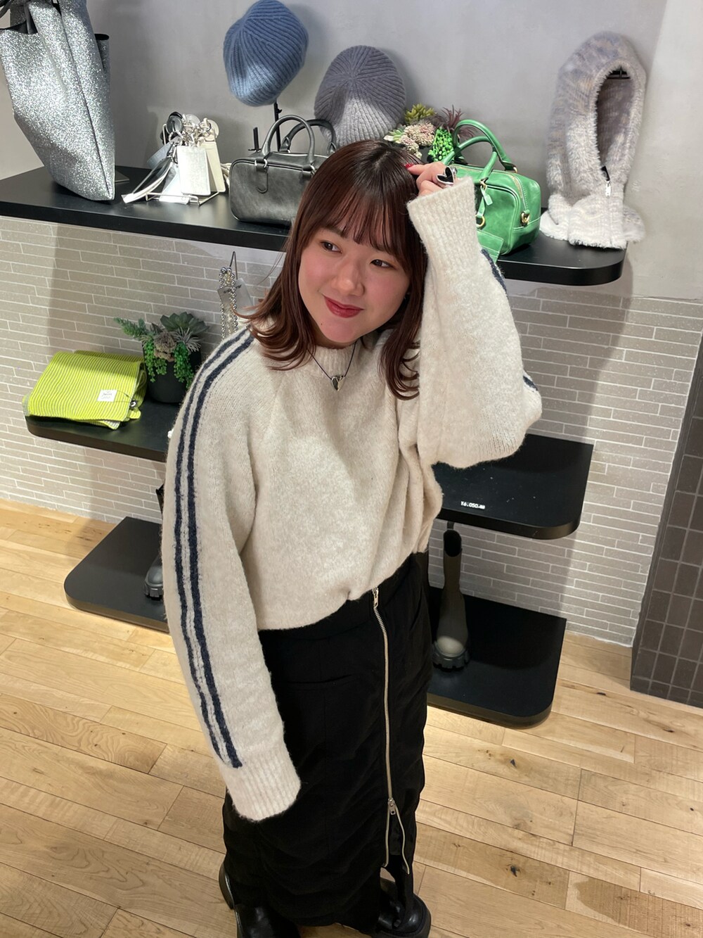 ブラック系のスカート、ホワイト系のニット/セーター、ブラック系のブーツを着用したレディースの冬コーディネートの3枚目の写真