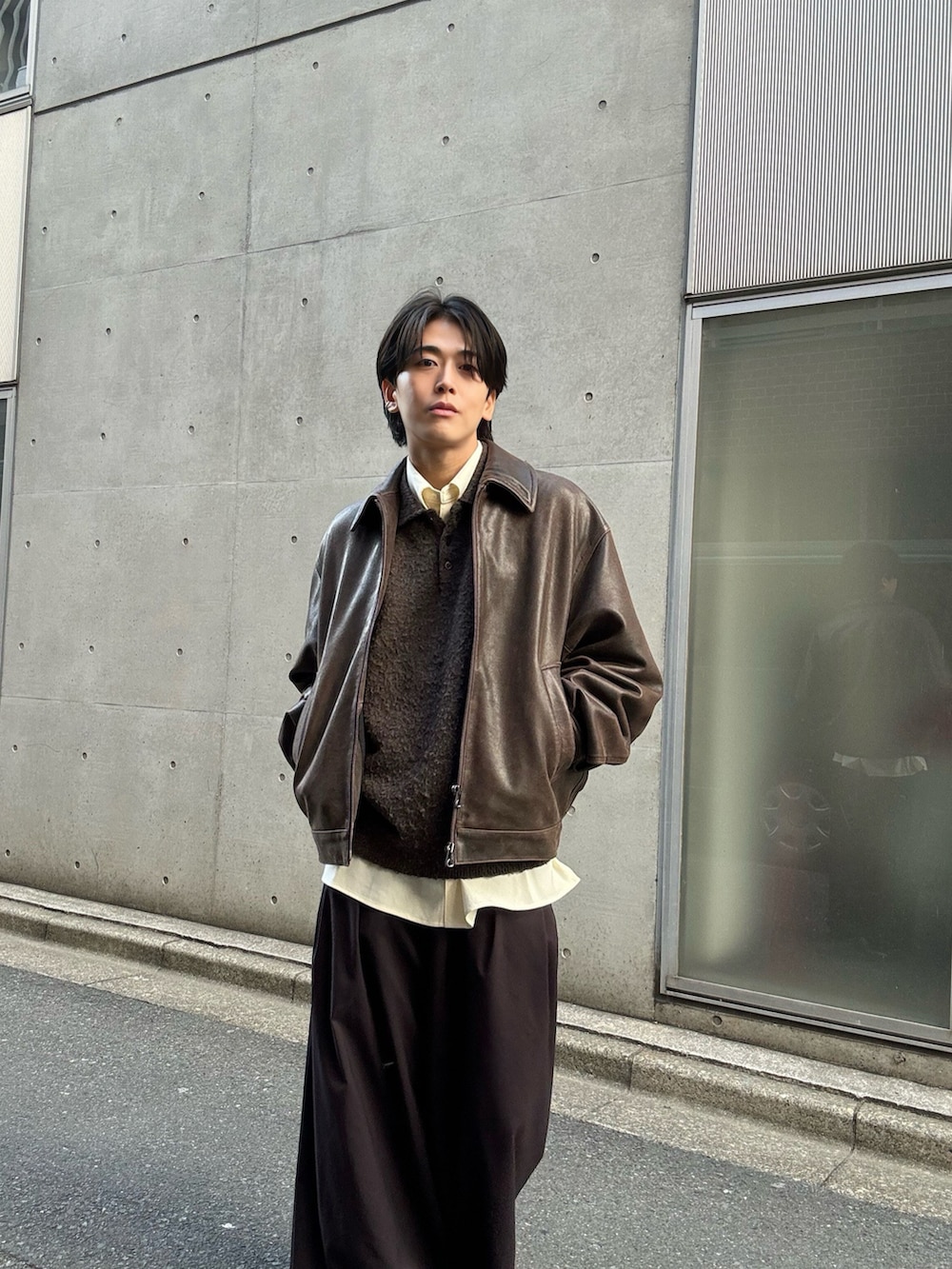 ブラウン系のニット/セーター、ホワイト系のシャツ/ブラウス、ブラウン系のスラックスを着用したメンズの冬コーディネートの2枚目の写真