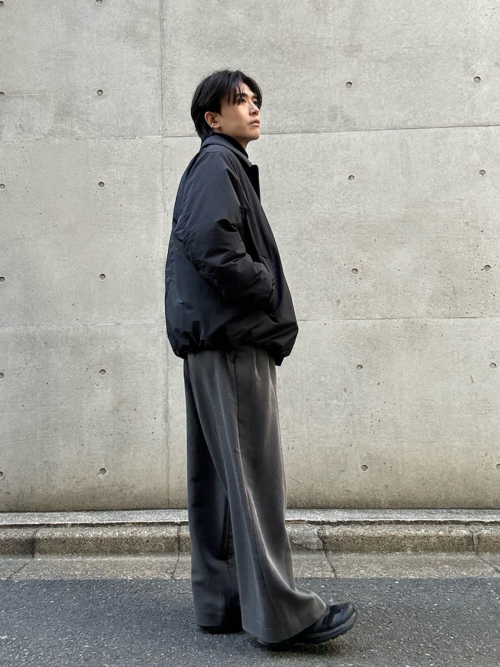 ブラウン系のニット/セーター、ブラック系のブルゾン、グレー系のスラックスを着用したメンズの冬コーディネートの2枚目の写真