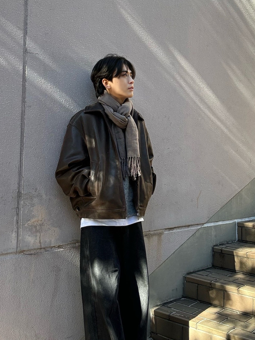 ブラック系のデニムパンツ、ホワイト系のTシャツ/カットソー、グレー系のニット/セーターを着用したメンズの冬コーディネートの2枚目の写真