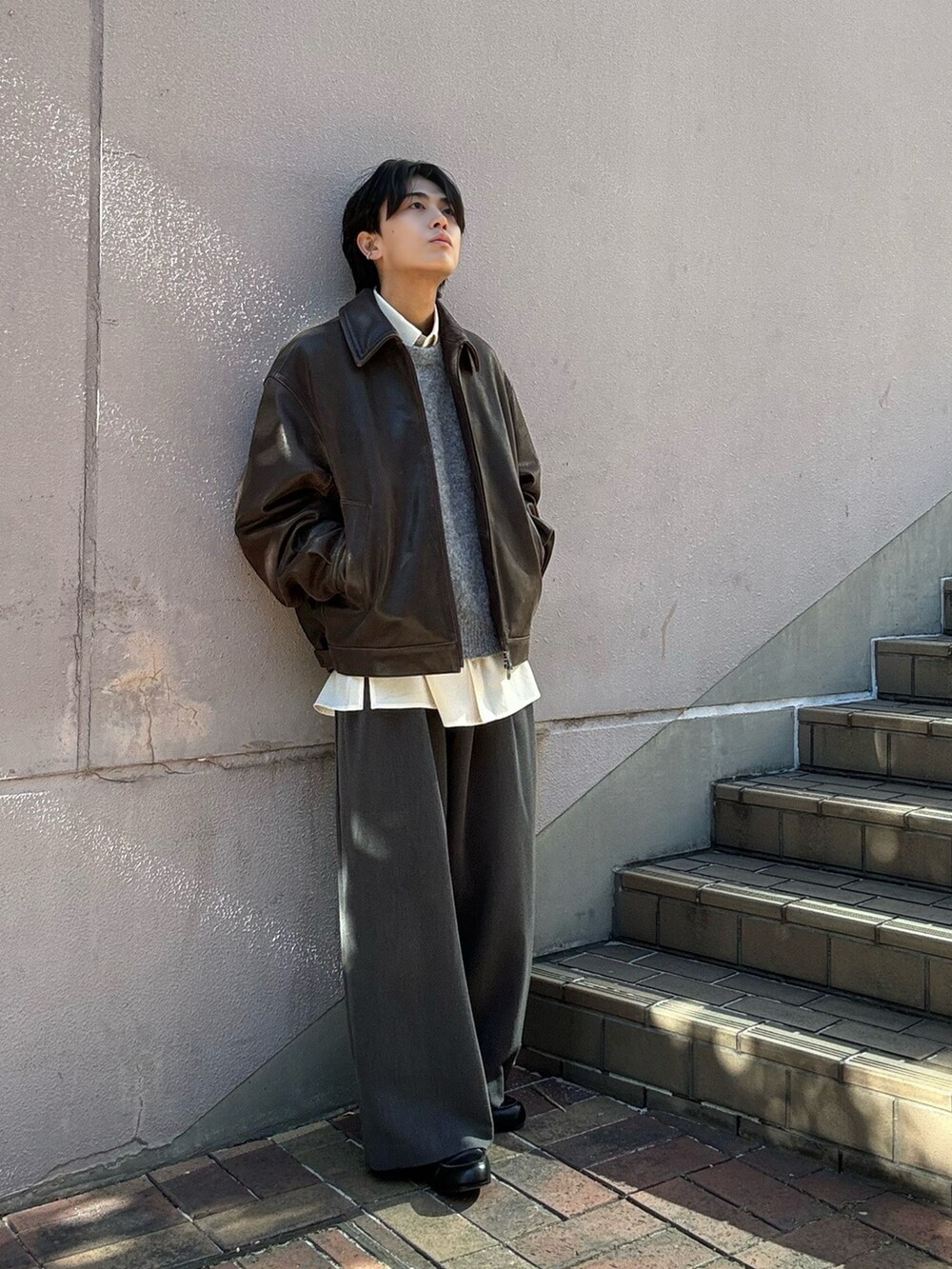 グレー系のニット/セーター、ホワイト系のシャツ/ブラウス、グレー系のスラックスを着用したメンズの冬コーディネートの2枚目の写真