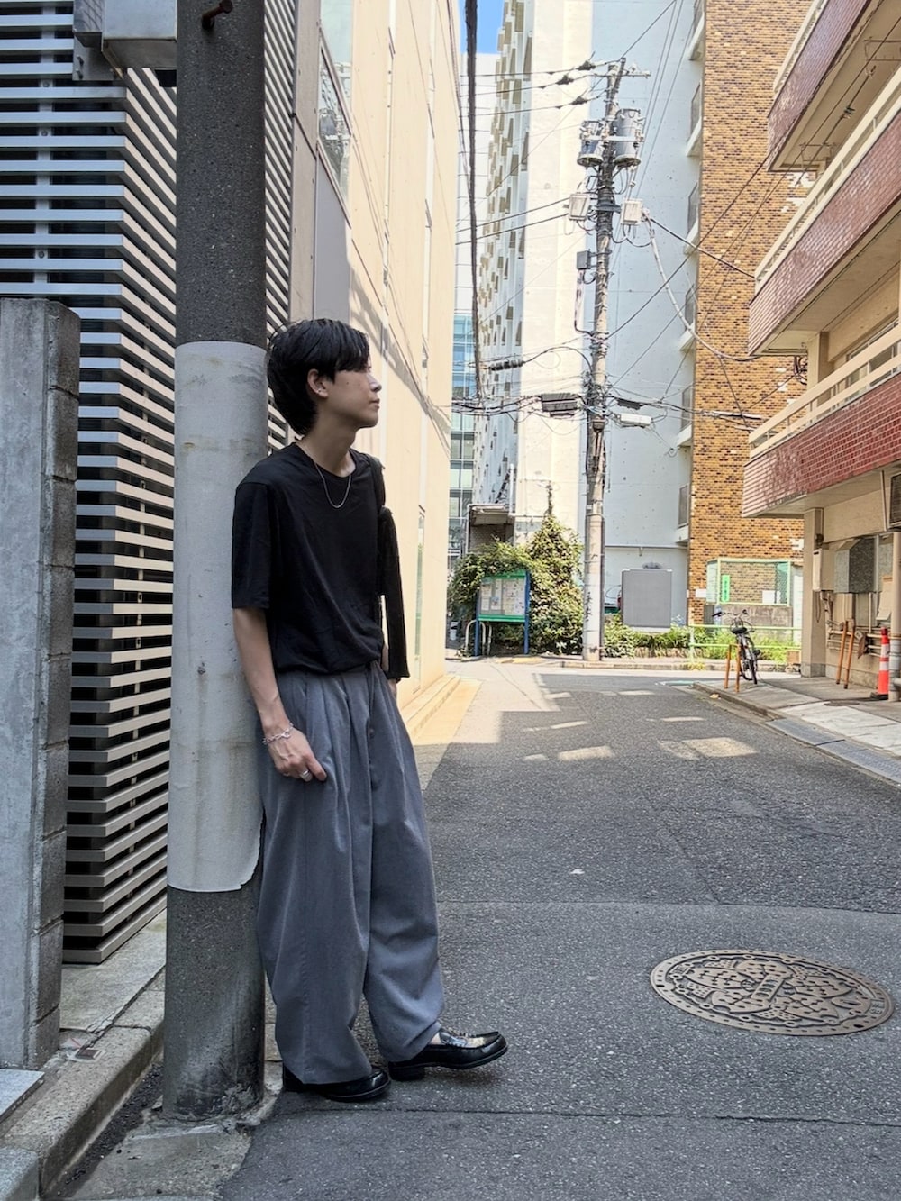 ブラック系のローファー、ブラック系のTシャツ/カットソー、ブラック系のショルダーバッグを着用したメンズの夏コーディネートの3枚目の写真