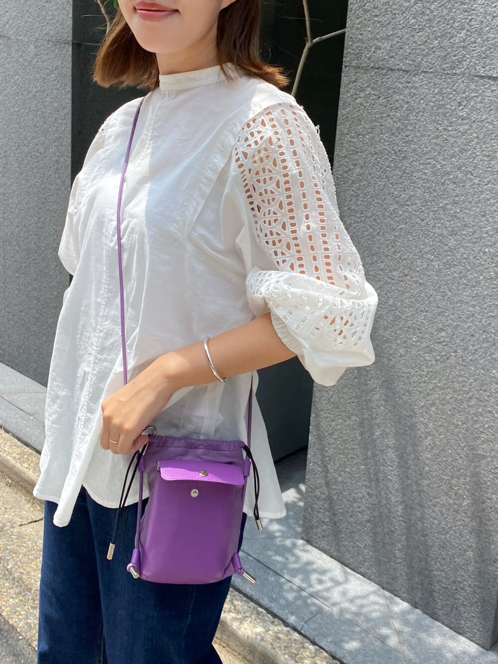 ホワイト系のシャツ/ブラウス、パープル系のショルダーバッグ、ブルー系のデニムパンツを着用したレディースの夏コーディネートの2枚目の写真