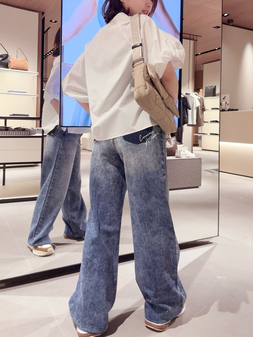 ブルー系のデニムパンツ、ホワイト系のシャツ/ブラウス、ベージュ系のバッグを着用したレディースの春コーディネートの2枚目の写真