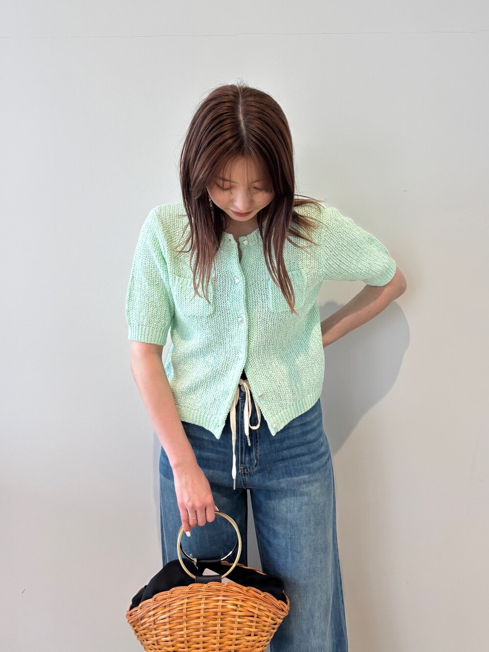 グリーン系のカーディガン/ボレロ、ブルー系のデニムパンツ、ブラウン系のかごバッグを着用したレディースの春コーディネートの3枚目の写真