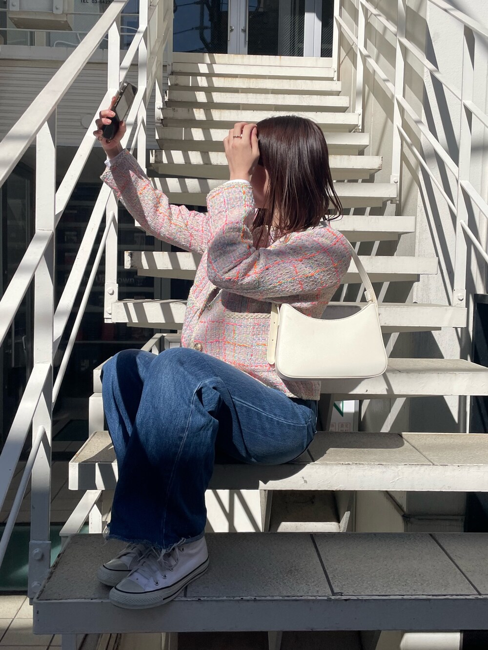 ブルー系のデニムパンツ、ピンク系のノーカラージャケット、ホワイト系のハンドバッグを着用したレディースの冬コーディネートの5枚目の写真