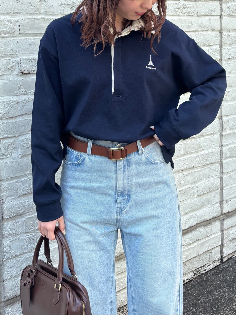 ブルー系のデニムパンツ、ブラウン系のハンドバッグ、ブルー系のTシャツ/カットソーを着用したレディースの春コーディネートの4枚目の写真