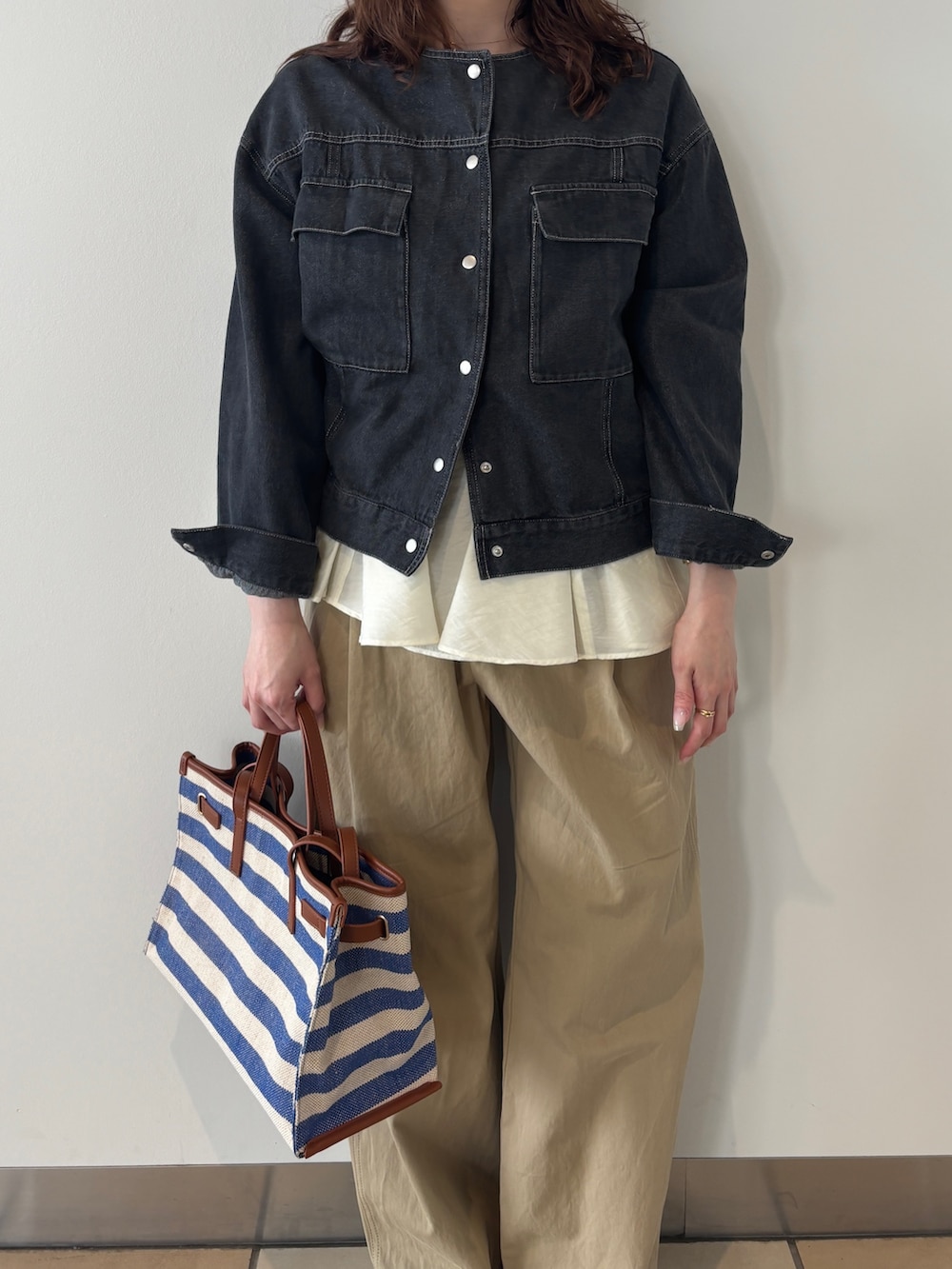 ブラック系のノーカラージャケット、ベージュ系のチノパンツ、ブルー系のショルダーバッグを着用したレディースの春コーディネートの4枚目の写真