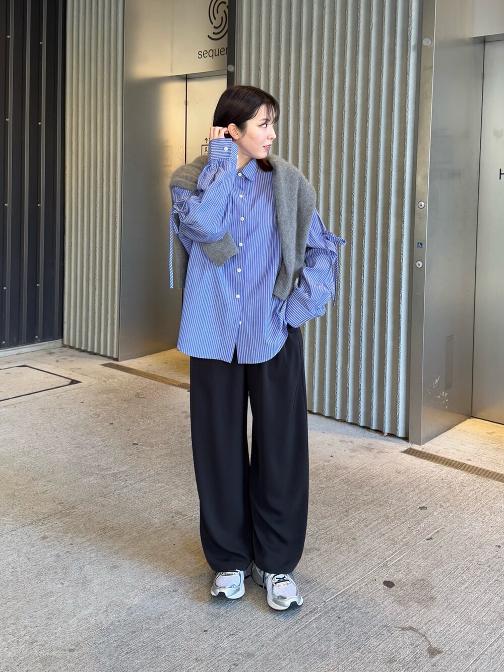 グレー系のニット/セーター、ブルー系のシャツ/ブラウスを着用したレディースの冬コーディネートの2枚目の写真