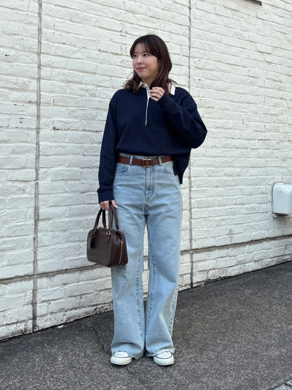ブルー系のデニムパンツ、ブラウン系のハンドバッグ、ブルー系のTシャツ/カットソーを着用したレディースの春コーディネートの2枚目の写真