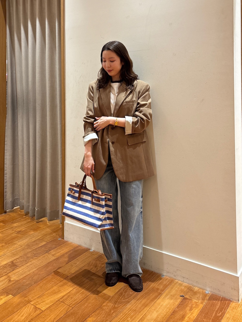 ブルー系のショルダーバッグ、ブルー系のデニムパンツ、ブラウン系のテーラードジャケットを着用したレディースの春コーディネートの2枚目の写真
