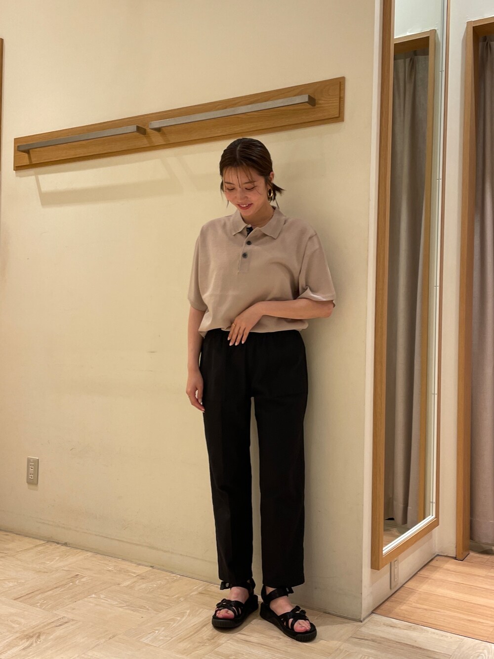 ベージュ系のポロシャツ、ブラック系のスラックス、ブラック系のサンダルを着用したレディースの春コーディネートの2枚目の写真