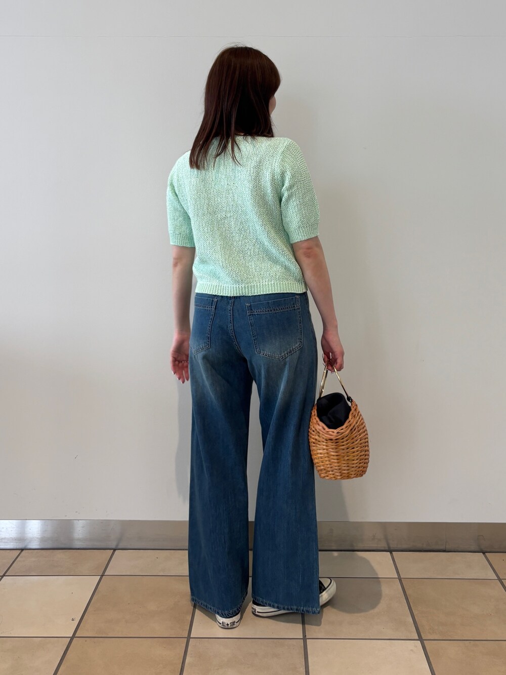 グリーン系のカーディガン/ボレロ、ブルー系のデニムパンツ、ブラウン系のかごバッグを着用したレディースの春コーディネートの2枚目の写真