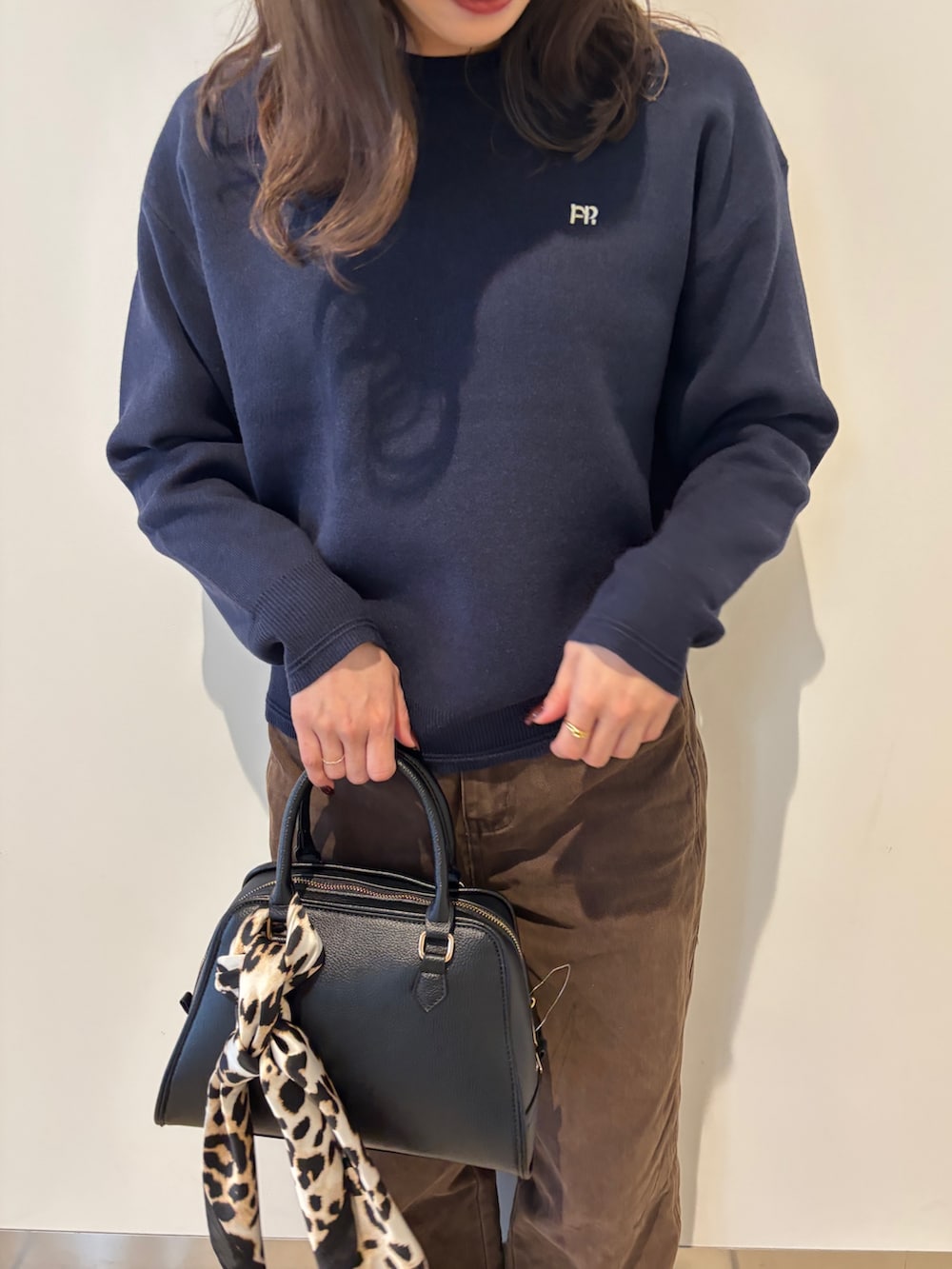 ブルー系のニット/セーター、ブラウン系のその他パンツ、ブラック系のショルダーバッグを着用したレディースの秋コーディネートの4枚目の写真