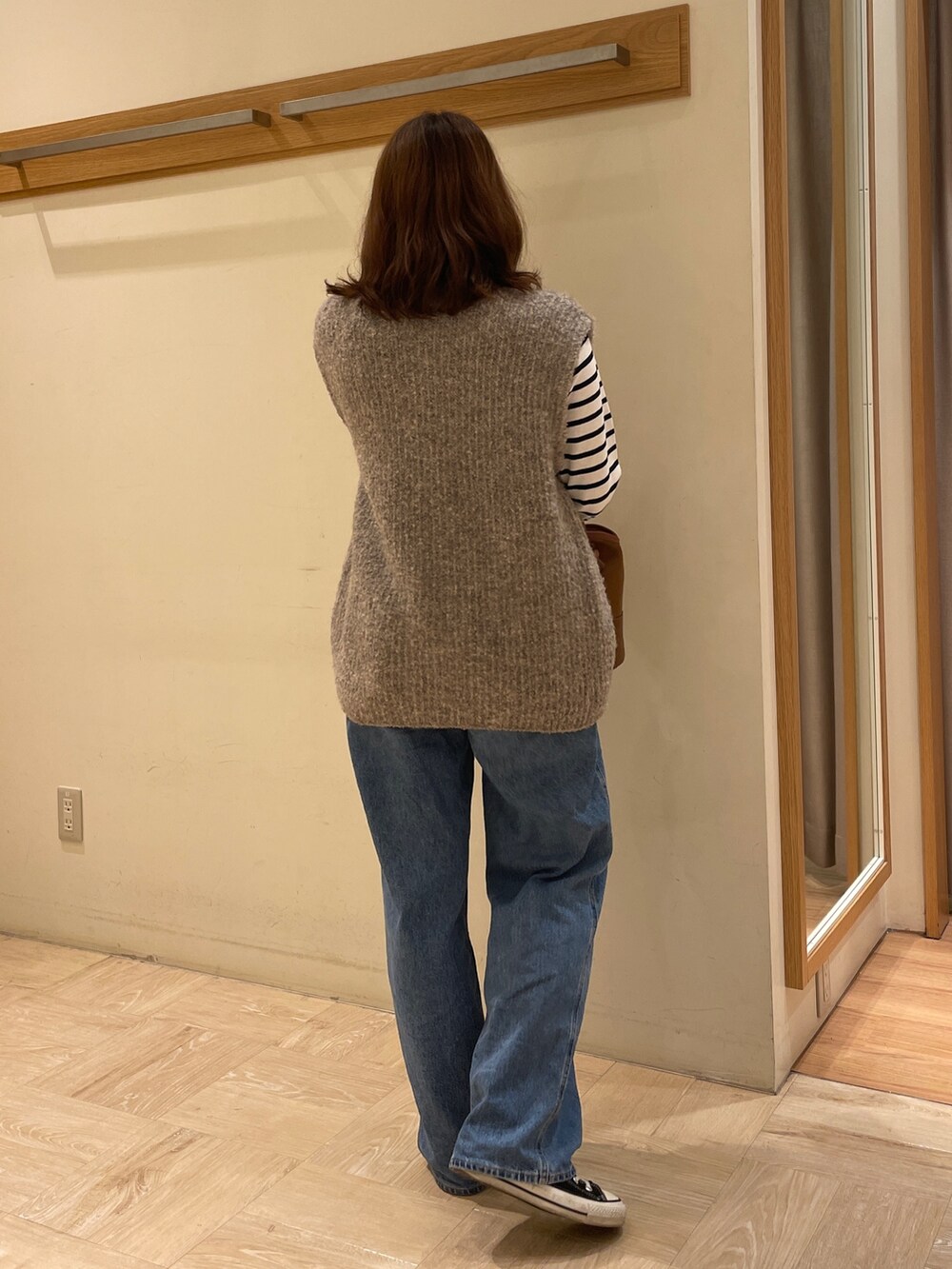 ベージュ系のベスト、ブルー系のTシャツ/カットソー、ベージュ系のショルダーバッグを着用したレディースの秋コーディネートの3枚目の写真