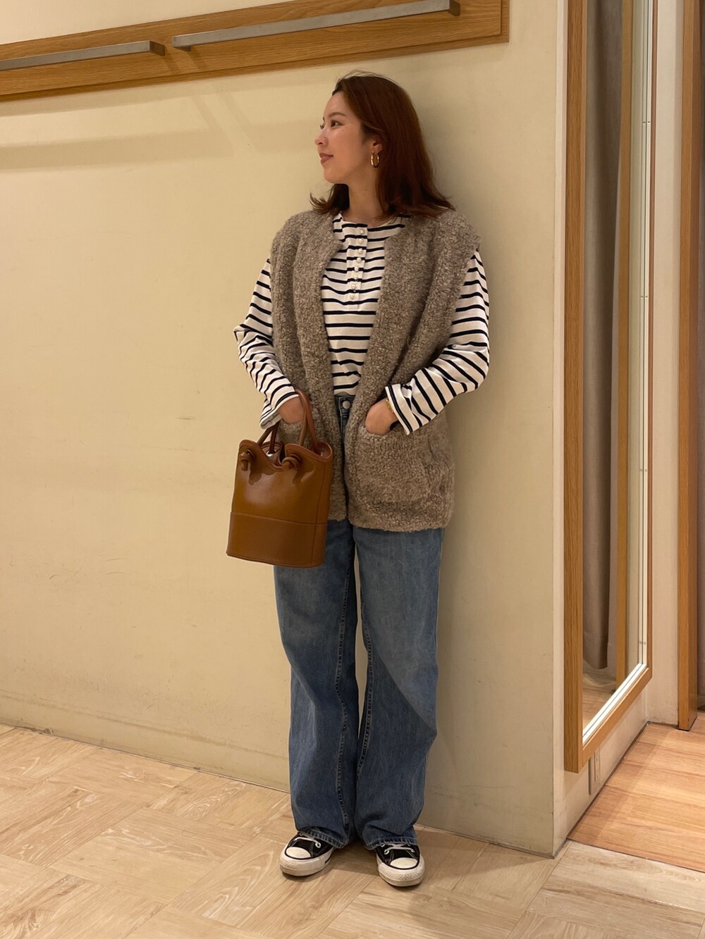 ベージュ系のベスト、ブルー系のTシャツ/カットソー、ベージュ系のショルダーバッグを着用したレディースの秋コーディネートの2枚目の写真