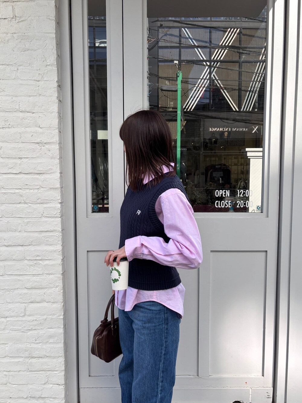 ピンク系のシャツ/ブラウス、ブルー系のベスト、ブルー系のデニムパンツを着用したレディースの春コーディネートの4枚目の写真