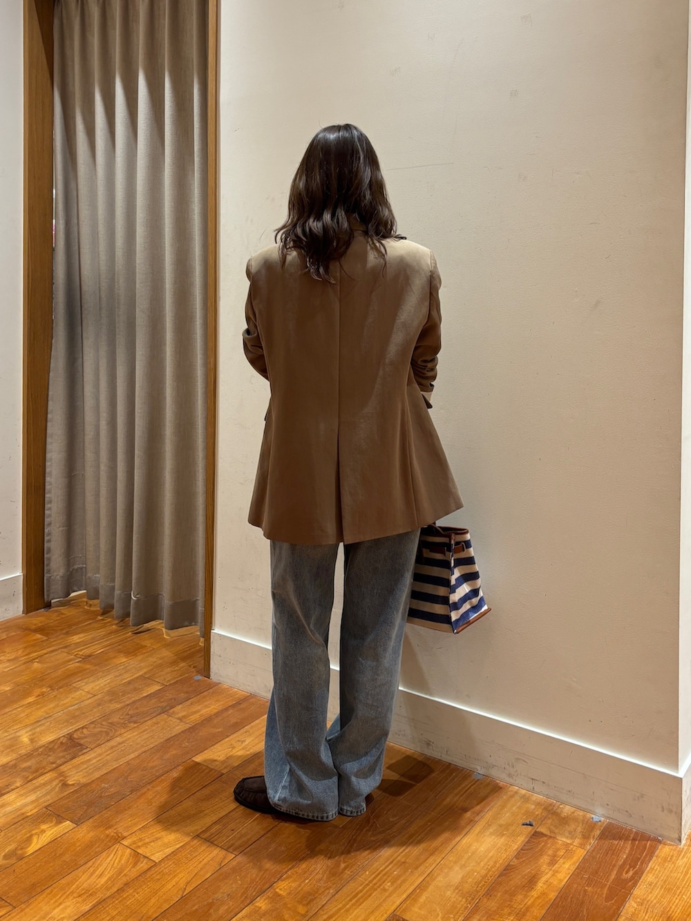 ブルー系のショルダーバッグ、ブルー系のデニムパンツ、ブラウン系のテーラードジャケットを着用したレディースの春コーディネートの3枚目の写真