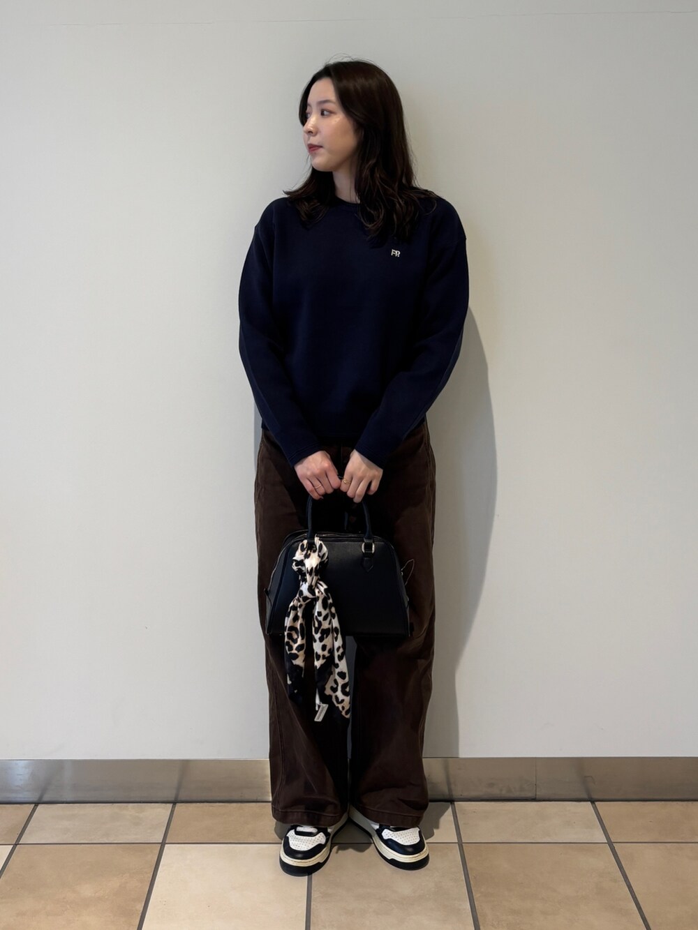 ブルー系のニット/セーター、ブラウン系のその他パンツ、ブラック系のショルダーバッグを着用したレディースの秋コーディネートの3枚目の写真