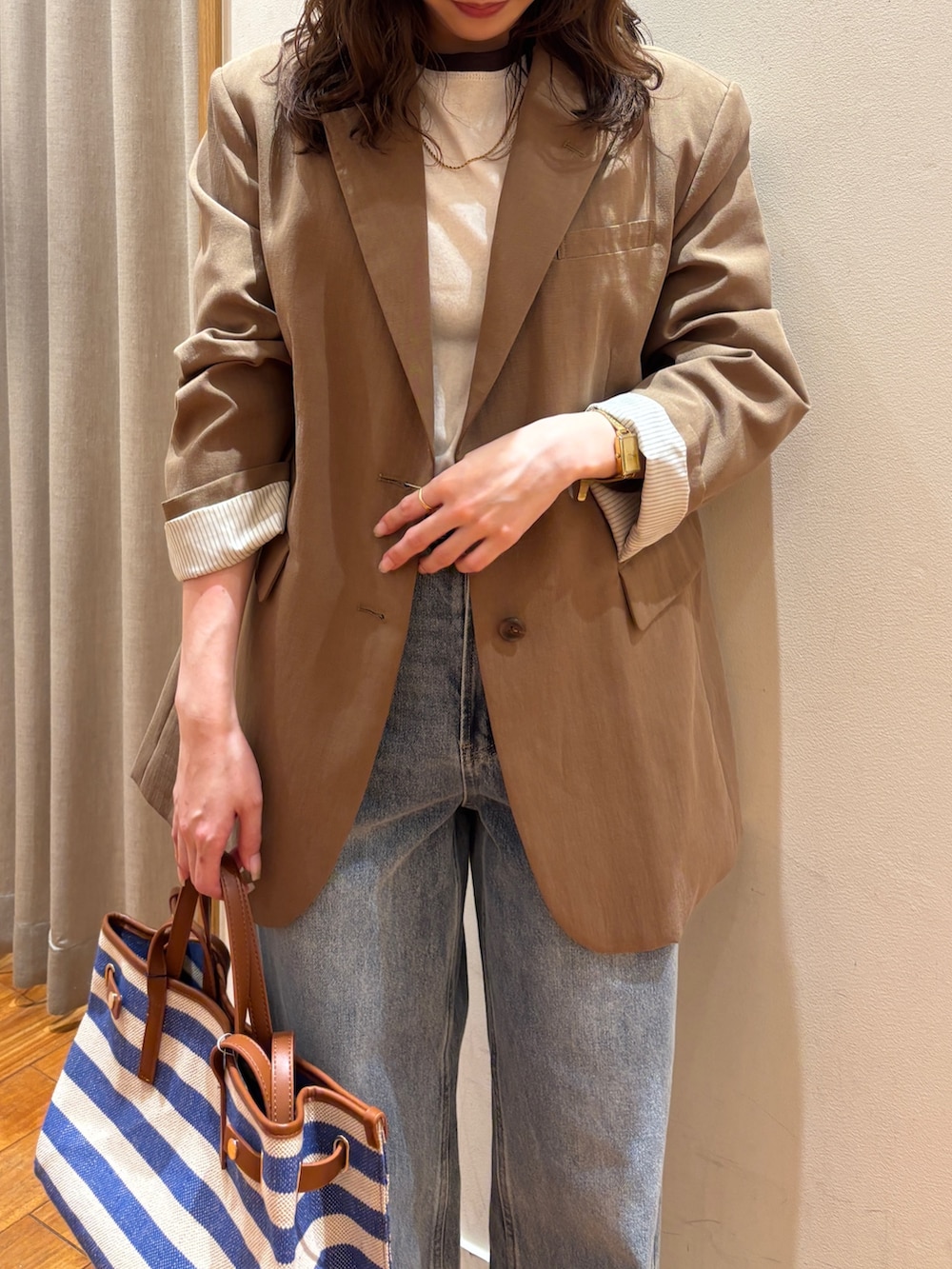 ブルー系のショルダーバッグ、ブルー系のデニムパンツ、ブラウン系のテーラードジャケットを着用したレディースの春コーディネートの4枚目の写真