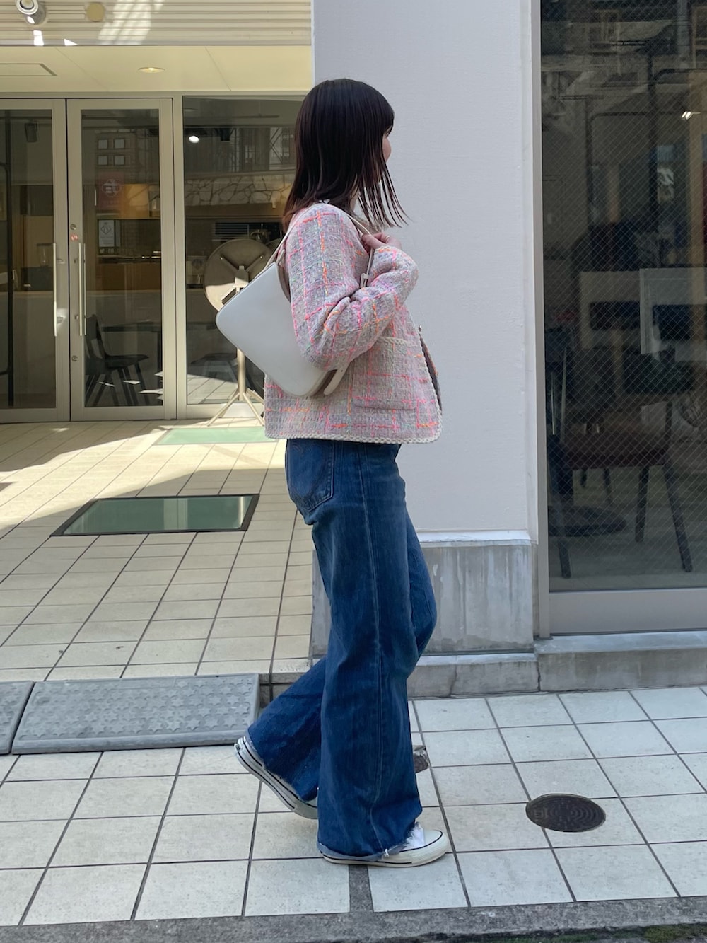 ブルー系のデニムパンツ、ピンク系のノーカラージャケット、ホワイト系のハンドバッグを着用したレディースの冬コーディネートの3枚目の写真