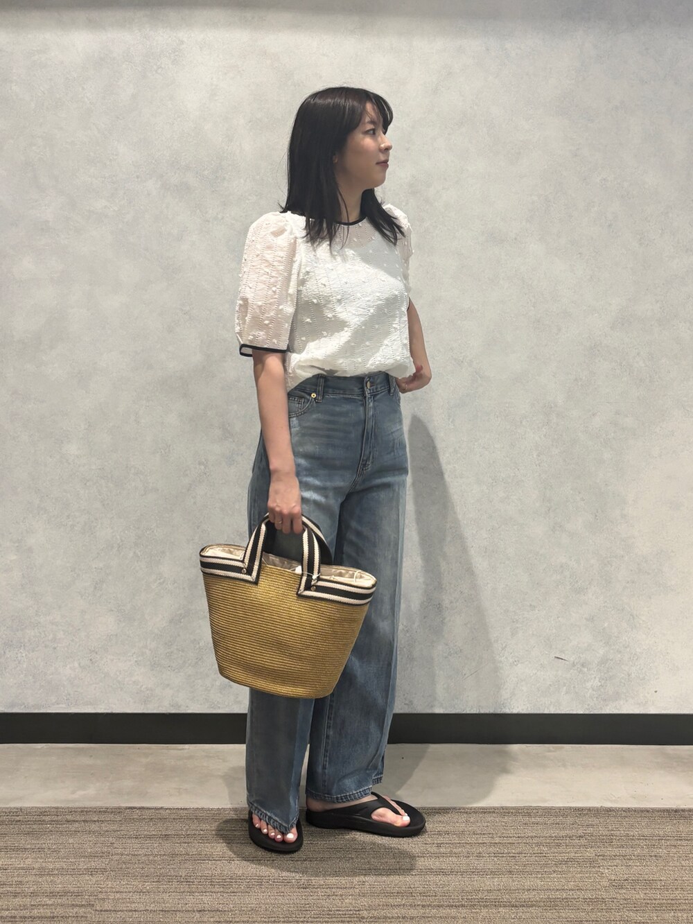 ブルー系のデニムパンツ、ベージュ系のかごバッグ、ホワイト系のシャツ/ブラウスを着用したレディースの夏コーディネートの3枚目の写真