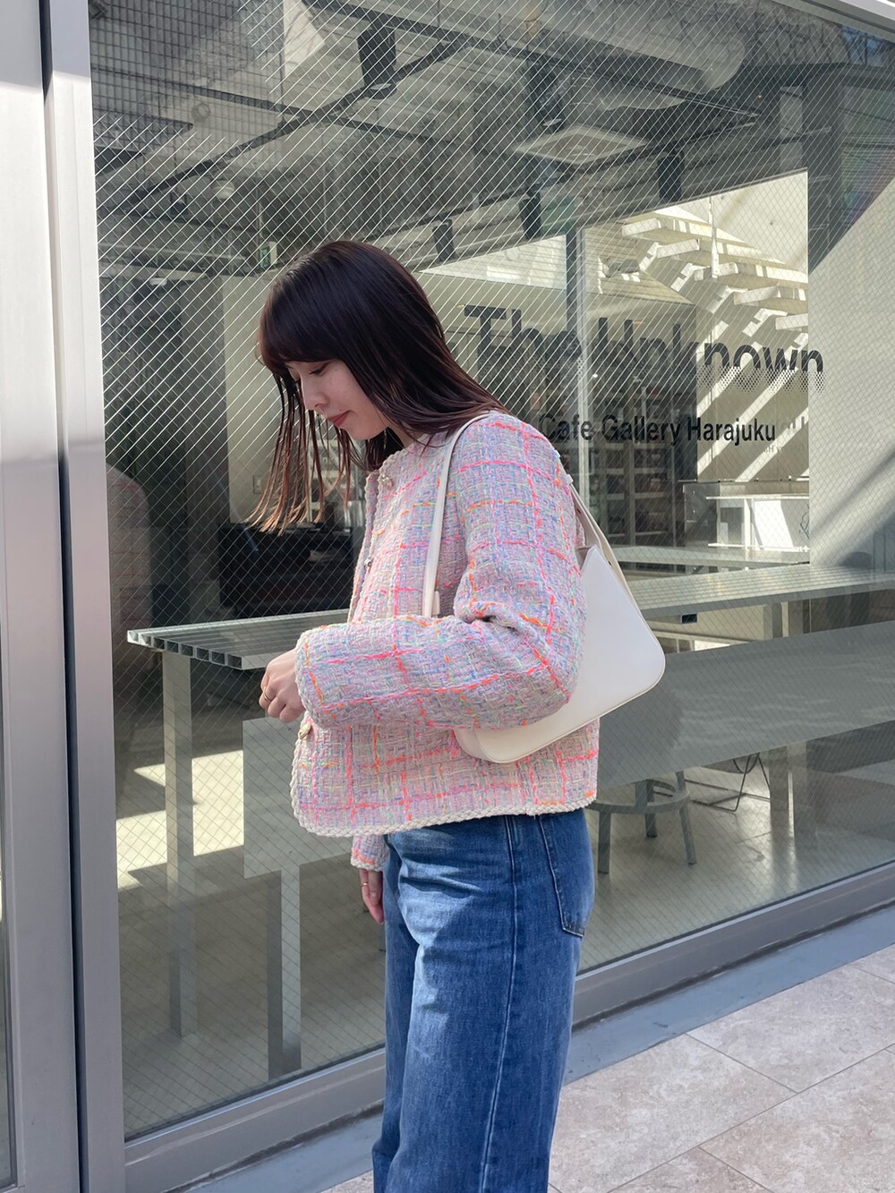 ブルー系のデニムパンツ、ピンク系のノーカラージャケット、ホワイト系のハンドバッグを着用したレディースの冬コーディネートの4枚目の写真