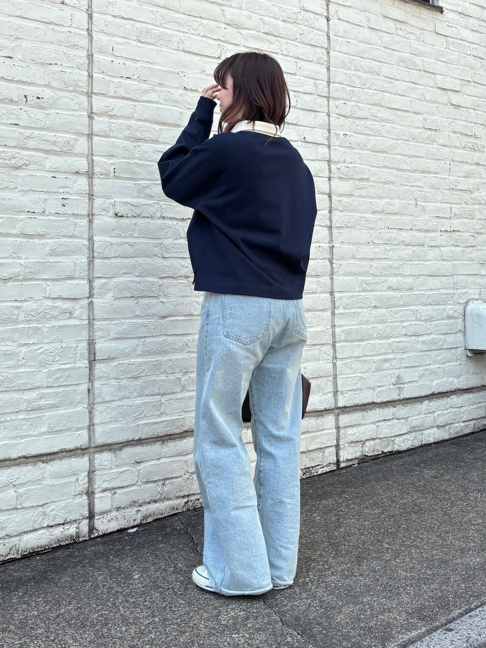 ブルー系のデニムパンツ、ブラウン系のハンドバッグ、ブルー系のTシャツ/カットソーを着用したレディースの春コーディネートの3枚目の写真