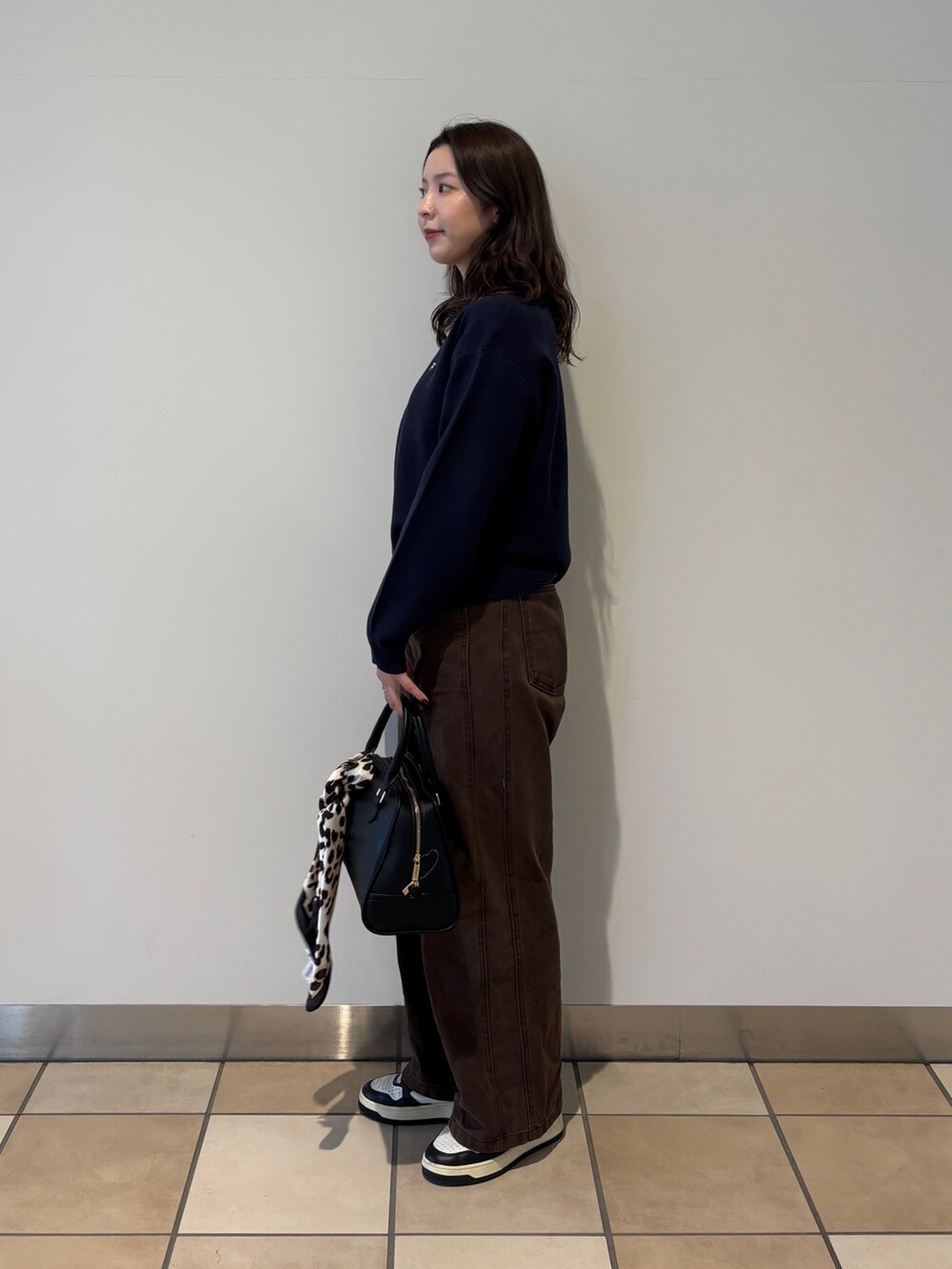 ブルー系のニット/セーター、ブラウン系のその他パンツ、ブラック系のショルダーバッグを着用したレディースの秋コーディネートの2枚目の写真