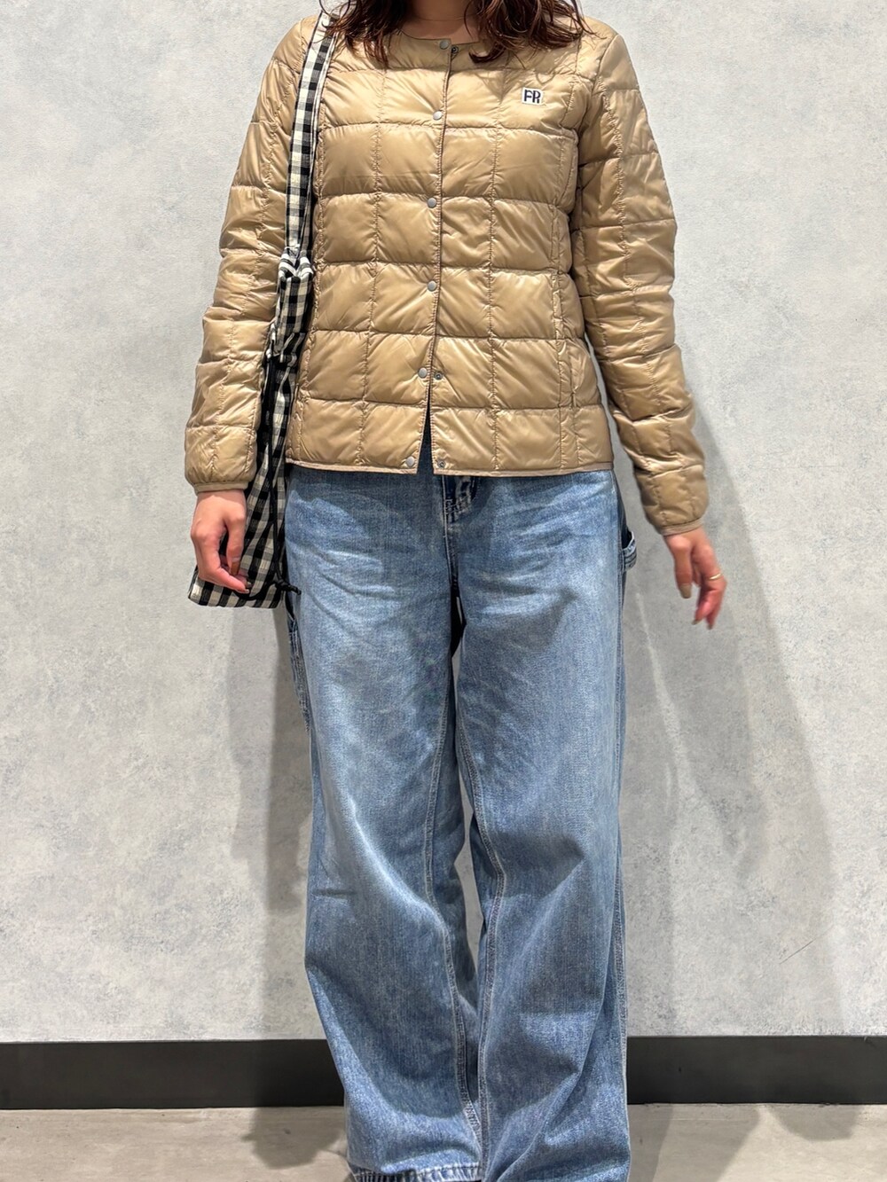 ブルー系のデニムパンツ、ベージュ系のダウンジャケット/コート、ホワイト系のトートバッグを着用したレディースの秋コーディネートの3枚目の写真