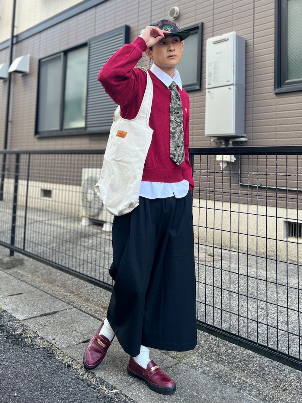 レッド系のニット/セーター、ホワイト系のシャツ/ブラウス、ブラック系のパンツを着用したメンズの秋コーディネートの2枚目の写真