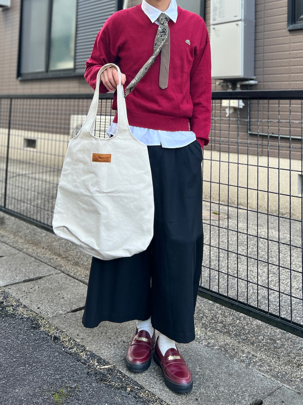 レッド系のニット/セーター、ホワイト系のシャツ/ブラウス、ブラック系のパンツを着用したメンズの秋コーディネートの3枚目の写真